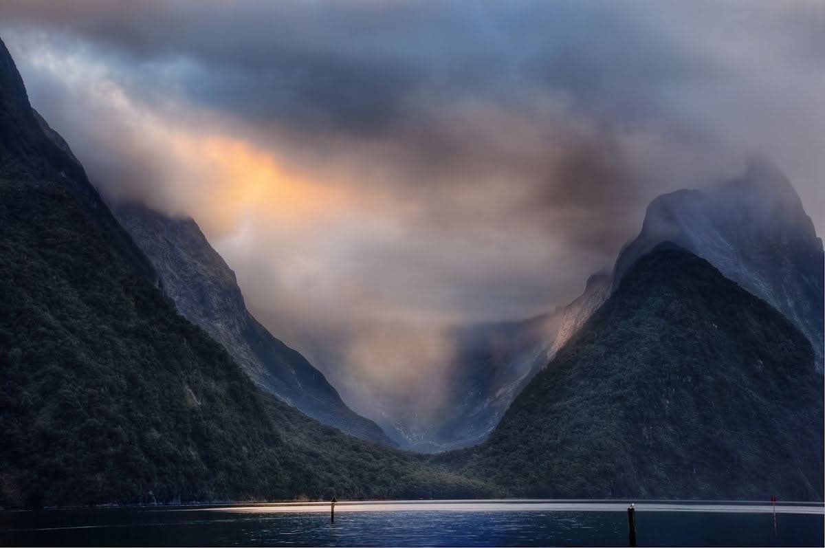 Storm light over the sheer fjord walls of Milford Sound, Fiordland National Park, New Zealand