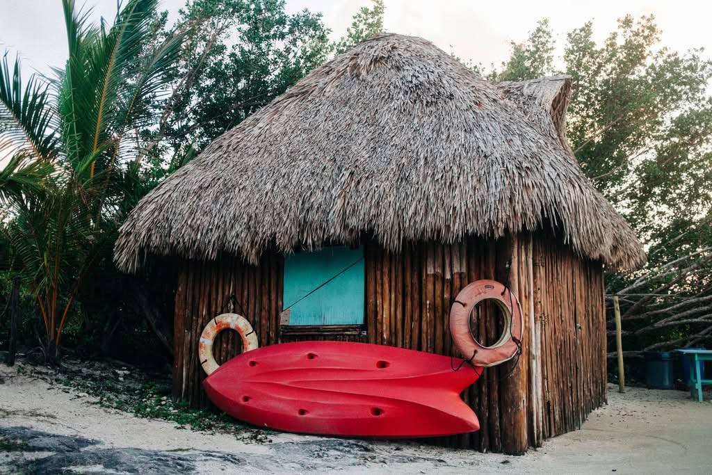 A charming beach hut with colorful kayaks and tropical palm trees, ideal for summer vibes