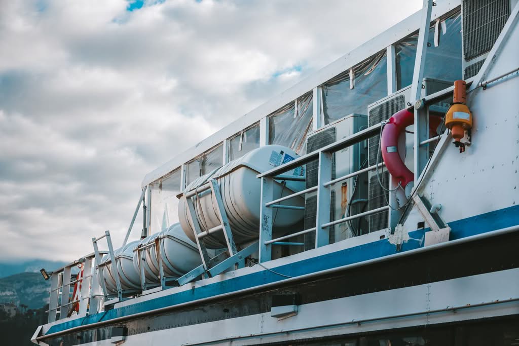 Side view of a modern boat deck equipped with lifebuoys and lifeboats, under cloudy skies