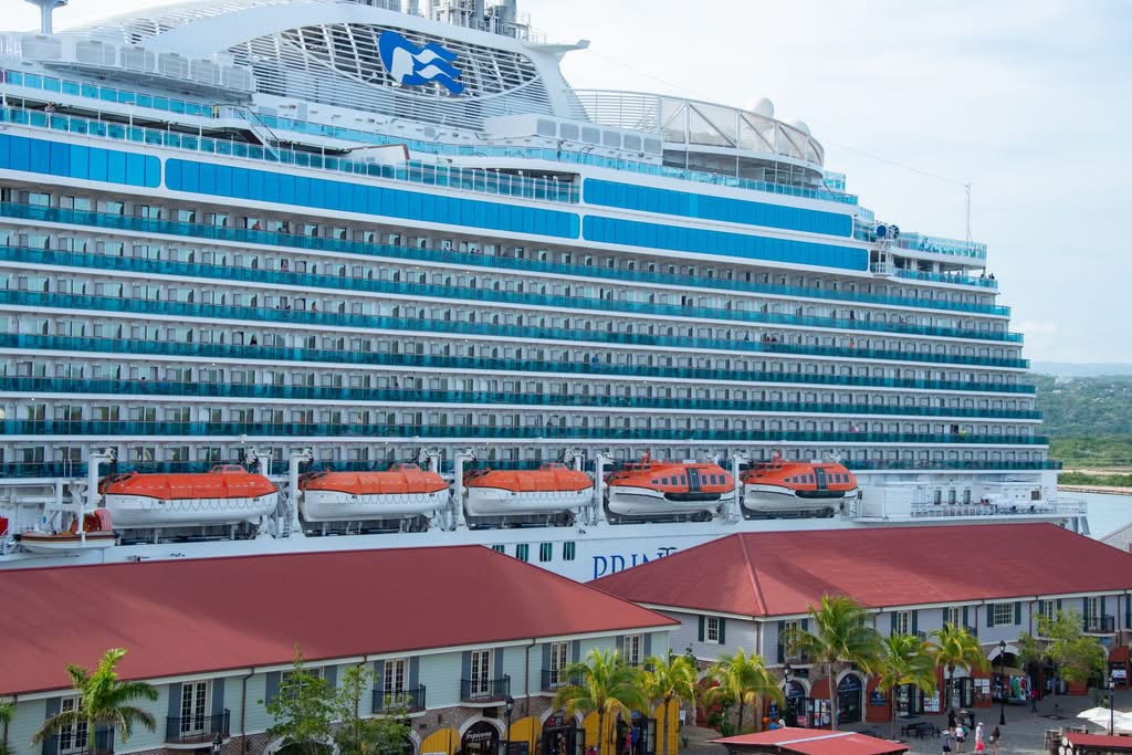 Large cruise ship Regal Princess docked at a vibrant harbor with visible lifeboats and luxurious amenities