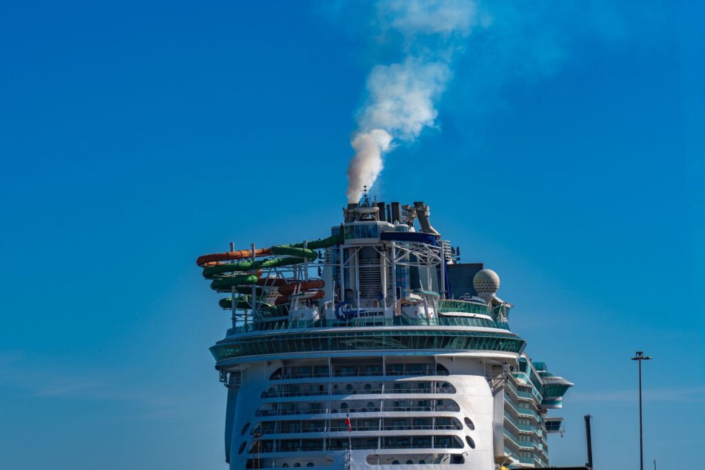 Top view of a cruise ship's smokestack emitting smoke against a clear sky in Cádiz port