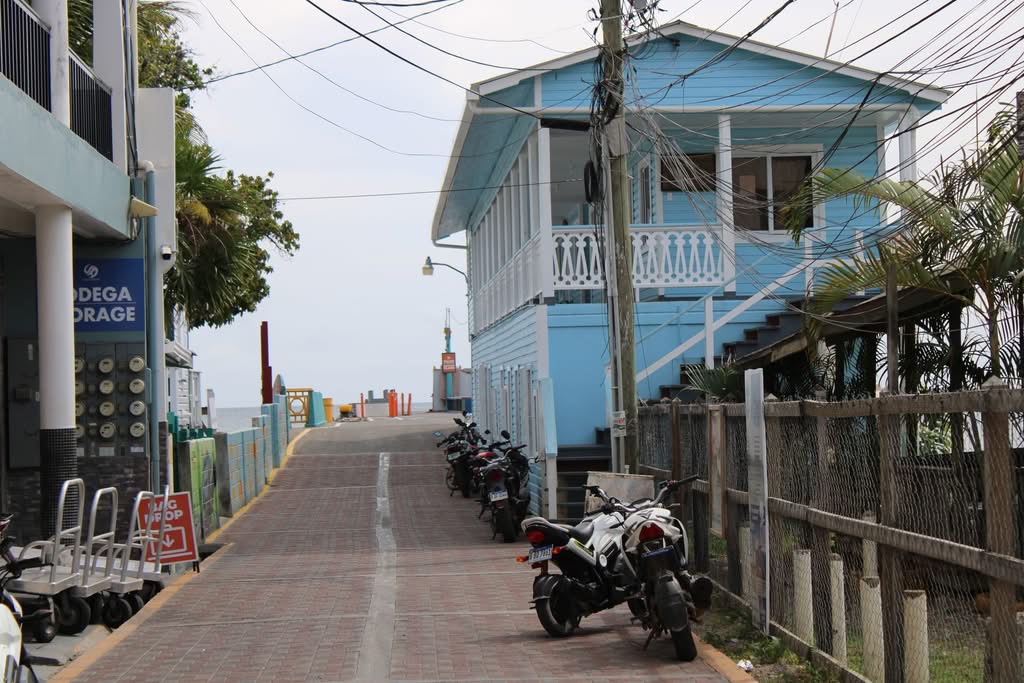 Picturesque street featuring a blue house and parked motorbikes in Utila, Honduras