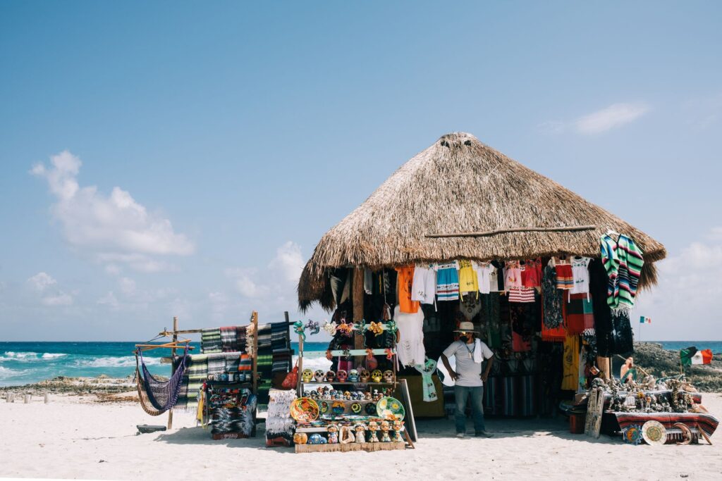 Beachfront market stall selling traditional clothing and souvenirs with ocean backdrop