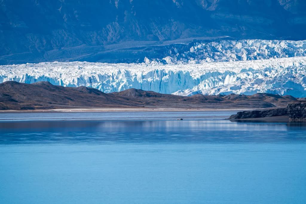 Scenic view of a glacier with icy cliffs meeting a tranquil fjord in Svalbard