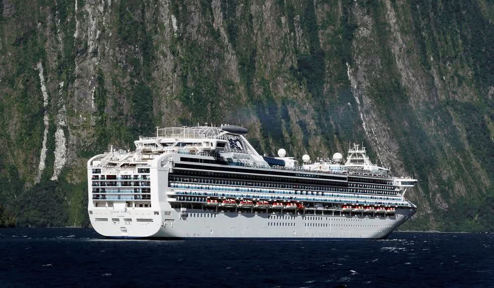 Cruise ship gliding through the cliffs of Milford Sound, New Zealand