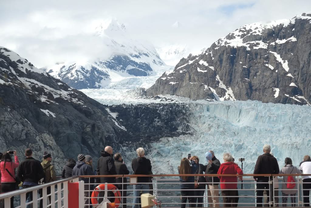 Cruise passengers at the rail watching an Alaskan tidewater glacier